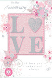 This anniversary card offers a tender, understated celebration of lasting love, its design composed in gentle layers of pastel pinks, pearl whites, and silvery greys reminiscent of early morning light along Dartford High Street before the day fully begins. At its centre, the word LOVE is presented in softly raised glitter, each letter subtly shimmering, while the O is replaced by a textured silver heart. This heart stands out like a small jewel, catching light and providing a focal point that feels both romantic and reassuringly solid. Around the central word, delicate blossoms in blush and mauve unfold with an almost watercolor softness. Their edges are fluid and slightly blurred, as though painted by hand, mirroring the care a florist in Dartford might use when selecting gentle, romantic stems for an anniversary bouquet destined for a home near Central Park. Fineness of line defines the slender stems, curling tendrils, and subtle butterflies that weave among the petals, adding quiet movement and a sense of whimsical grace. The background stays soft and unobtrusive, allowing the flowers and central motif to gently command attention. At the top, the phrase On Our Anniversary appears in a discreet, flowing script, while near the bottom the words I love you today and always echo the same tone of heartfelt sincerity. The whole composition feels like a whispered promise captured on card stock-light as a breath yet deeply meaningful-perfect for keeping as a cherished reminder of shared years and the thoughtful care that often accompanies a hand-delivered anniversary bouquet in Dartford.